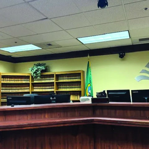 Courtroom Picture Judge's seat in the courtroom, computers behind and elevated desk with a bookshelf in the background